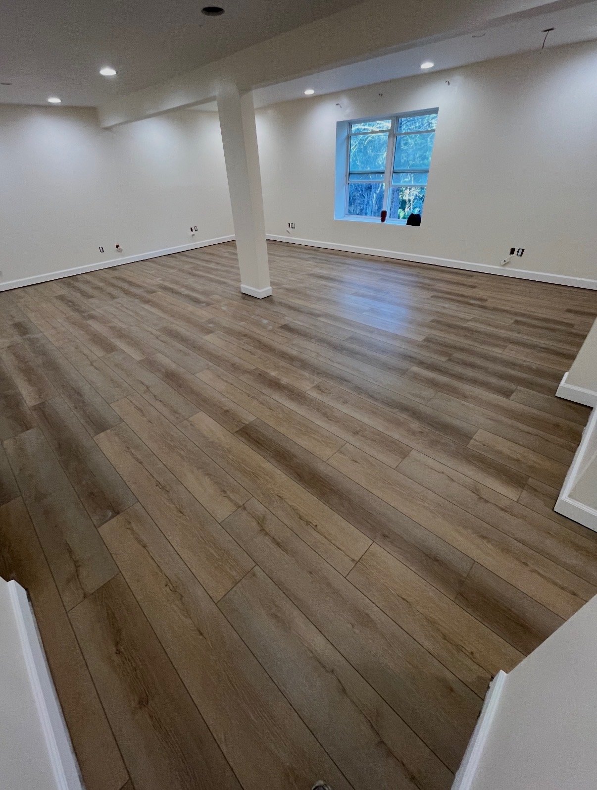 Finished wood-look flooring in a large open basement room