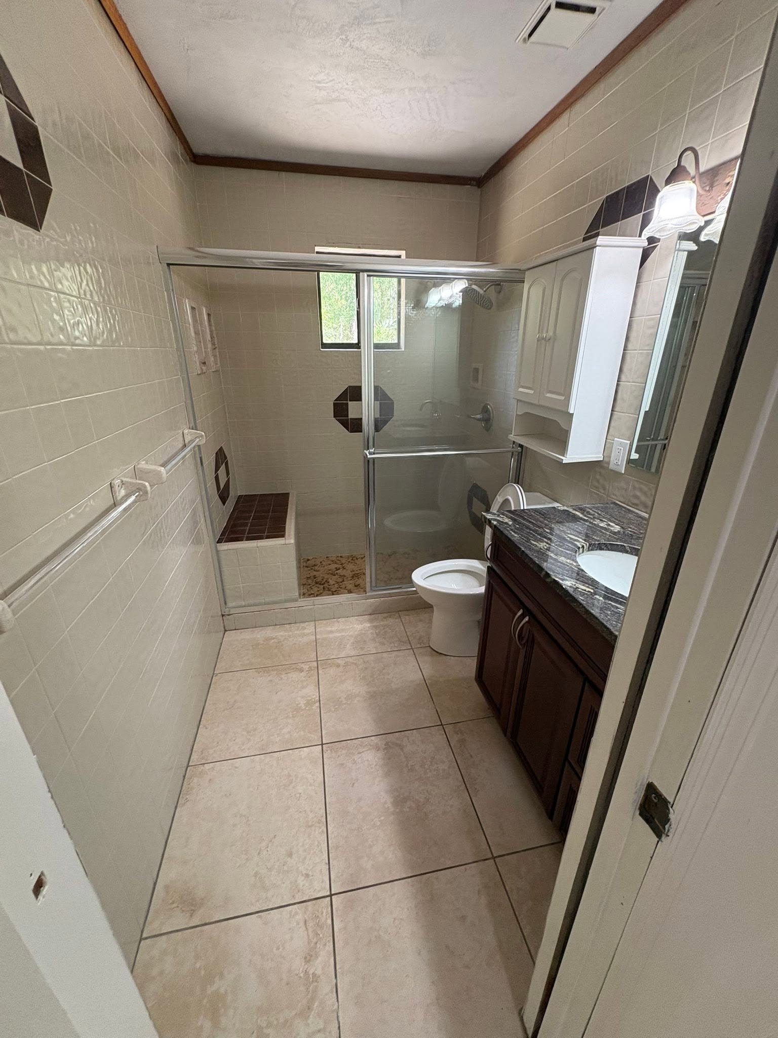 Dated bathroom before remodel with tile shower and dark vanity